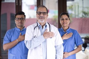 Positive doctor and nursing staff with hands on chest